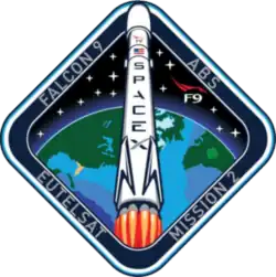 A diamond-shaped emblem with blue borders encasing an artistic depiction of a Falcon 9 rocket launching to space.