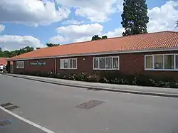 Redbrick long low building stretching away from camera on a sunny day with a dappled sky