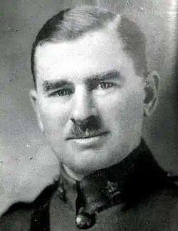 Brown-haired man with moustache. He is wearing a military uniform.