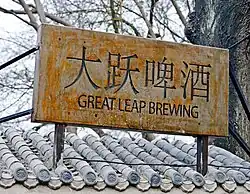 A slightly rusted gray metallic sign with "Great Leap Brewing" written on it and four Chinese characters below