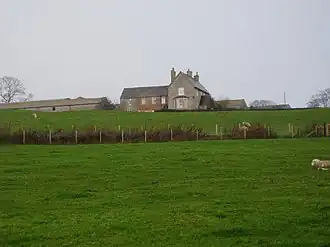 View across garden to fields. Small redbrick cottage to left.