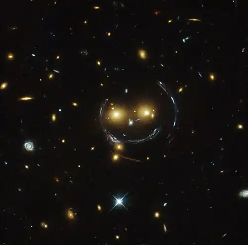"Smiley" image – galaxy cluster (SDSS J1038+4849) & gravitational lensing (an Einstein ring) (HST).[30]