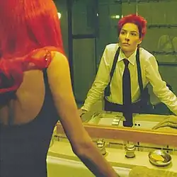 Halsey as a woman staring into a mirror to see her as a man