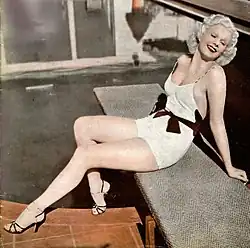 Color photo of Harlow in a swim suit sitting beside a pool