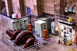 A picture taken from above looking down on a fenced off control room where many large panels with instruments and controls.