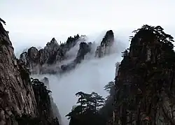 Mountain with several granite peaks, partially covered by clouds