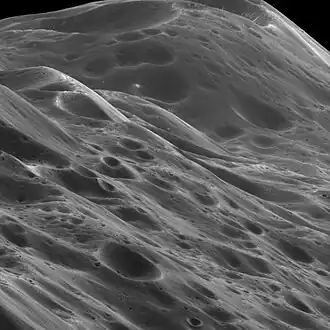 Image 7 Iapetus Photo credit: Cassini orbiter A close-up of 10&nbsp;km (6.2&nbsp;mi) high mountains within the equatorial ridge on Saturn's moon Iapetus, photographed by the Cassini orbiter. Above the middle of the image can be seen a place where an impact has exposed the bright ice beneath the dark overlying material. The image was taken on September 10, 2007, with the Cassini spacecraft narrow-angle camera at a distance of approximately 3,870&nbsp;km (2,400&nbsp;mi) from Iapetus. More selected pictures