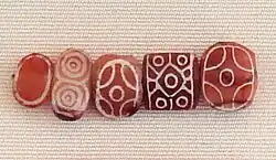 Indian carnelian beads with white design, etched in white with an alkali through a heat process, imported to Susa in 2400–2100 BC. Found in the tell of the Susa acropolis. Louvre Museum, reference Sb 17751.[67][68] These beads are identical with beads found in the Indus Civilization site of Dholavira.[69]