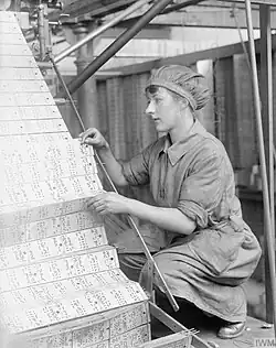 A female worker changing jacquard cards in a lace machine in a Nottingham factory (1918).