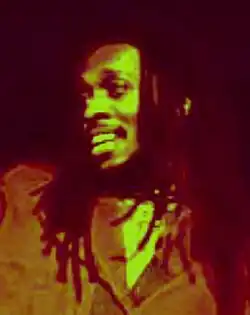 blurry image of Ini Kamoze grinning and looking right of camera