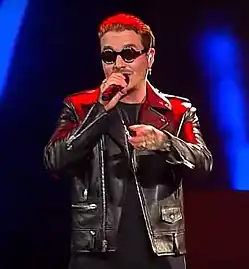 J Balvin, facing front, holding a microphone.
