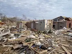 EF3 damage example--A few parts of affected buildings are left standing. Well-built structures lose all outer and some inner walls. Unanchored homes are swept away, and homes with poor anchoring may collapse entirely. Trains and train cars are all overturned. Small vehicles and similarly sized objects are lifted off the ground and tossed as projectiles. Wooded areas suffer an almost total loss of vegetation and some tree debarking may occur.