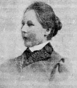 3/4 view of head and shoulders of middle-aged white woman with dark hair in bun