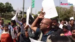 Crowd of people marching on the street; some of them are holding signs