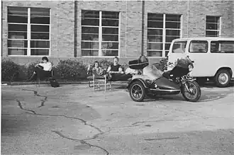 Left to right on the couch: Eric Bussen, Steve Hendren, Matt Koebbe behind his motorcycle with sidecar outside old T-6 KMNR. On the chair is Sylvia Carty (not yet Carty at this point). It was a beautiful Spring day, and they had to pull the furniture out to enjoy the day.