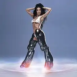Perry wearing the white knit bikini and bionic legs from the music video. She has both arms behind her head.