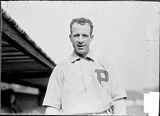 A smiling dark-haired man in a white baseball jersey with a block "P" over the left breast
