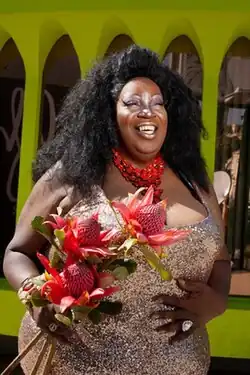 Lady Red Couture smiling and holding flowers