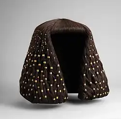 A short brown wig fitted with hundreds of gold rings