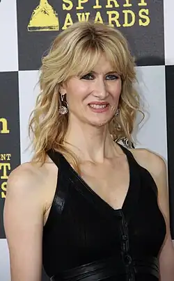 A blonde woman in a black dress, looking slightly towards the right