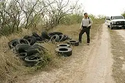 Image of an officer looking at illegally dumped tires on the side of the road.