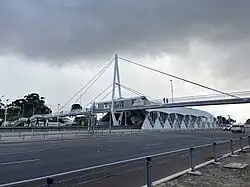 A cable-stayed footbridge across a freeway connecting with the station