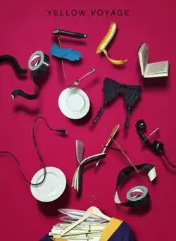 The album's cover art. In a similar style to the Yellow Dancer cover, it is of a crimson background scattered with everyday objects such as plates, bananas, books, and tape, with the title "YELLOW VOYAGE" in black at the top.
