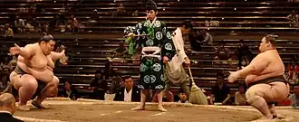 Two sumo wrestlers standing at opposite sides of the ring