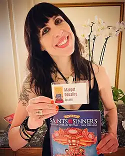 Author Margot Douaihy posing with ID card and a catalog at the New Orleans Saints & Sinners LGBTQ+ Literary Festival in 2023.
