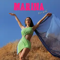 Welsh singer-songwriter Marina Diamandis appears in a sleeveless green dress that partially exposes the sides of her midriff; a blue cape flows in the wind behind her and she stands in a field with the sky in the background. The words "Marina", which was written in a capitalized and bright pink font, and "Man's World", which was written in a white cursive font, appear.
