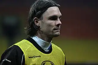 A man in his late twenties wearing a training bib.