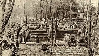 Sepia photograph of men constructing a log cabin.