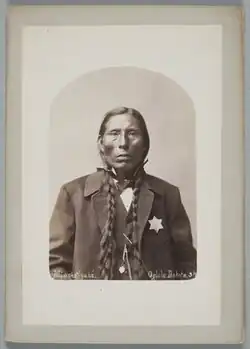 Sepia-toned head shot of a man in a suit with a badge