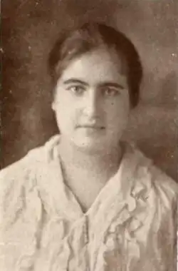 A young white woman with dark hair and eyes, wearing a ruffled white blouse