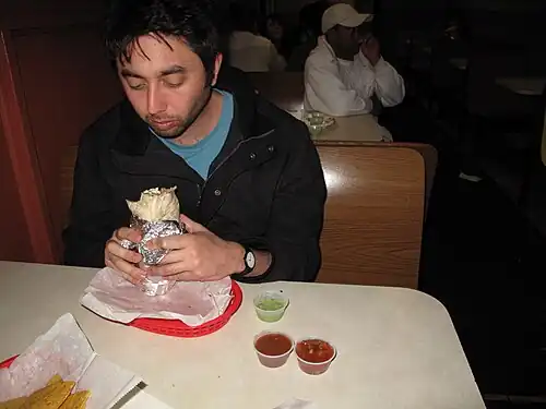 A man eats a Mission-style burrito in San Francisco, circa 2010.