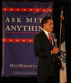 Mitt Romney addressing an audience from atop a stage