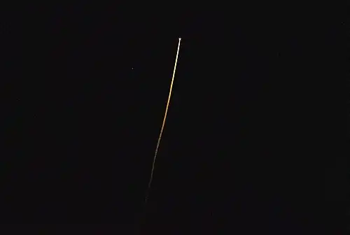 Crew Dragon Endurance streaks across the night sky as it reenters Earth's atmosphere.
