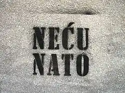 A white wall with black spray painted words "Neću Nato" on it.