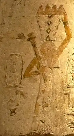 Painted relief of a woman with a basket full of food on her head.