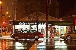 A shop on a street corner labelled, "99 Cent Fresh Pizza"