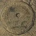 Manhole cover in the road, covering the actual tri-point monument, 1990