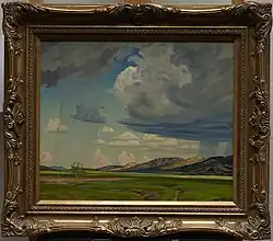 A painting of the sky surrounded by a gilded, golden frame. The light green ground takes up a small portion of the bottom, with tire tracks streaked across. Behind the greenery are faded purple mountains, with the main focus of the picture being on the large, looming clouds and the bright blue sky. Streaks of blurry rain are visible along the horizon.