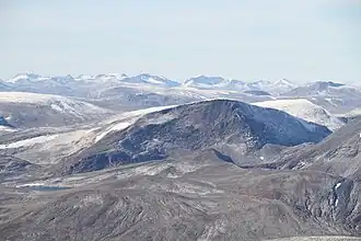 Rugged mountains of various elevations, the higher peaks and slopes featuring patches of snow