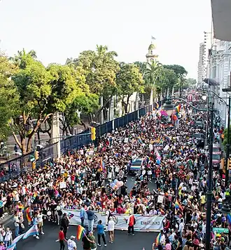 An aerial view of a parade of people holding LGBT flags.