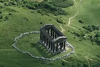 An aerial view of Penshaw Monument, surrounded by hundreds of people in white clothing