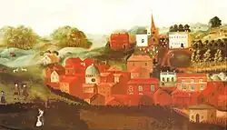 a number of buildings, mainly red, in front of a church on a hill and a row of small trees
