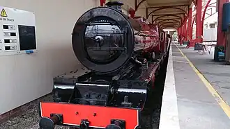Maroon coloured miniature locomotive sits in the station