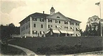 A three-story rectangular building on a hill