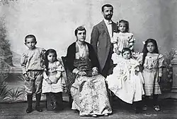 Photograph of Pontic Greek man, woman, and their children. The man is dressed in Western clothes, the woman in traditional costume.