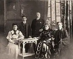 Old photo of five Pontic Greeks in western dress, seated or standing inside.